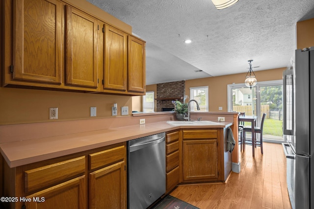 1005 Pleasant Dale Dr, Wilmington, NC 28412 - kitchen featuring appliances with stainless steel finishes, a peninsula, brown cabinetry, light countertops, and light wood-style flooring