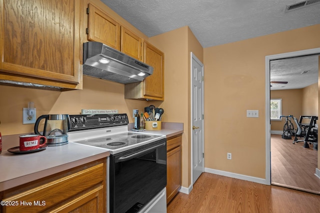 1005 Pleasant Dale Dr, Wilmington, NC 28412 - kitchen with white electric stove, under cabinet range hood, light wood-style floors, a textured ceiling, and light countertops