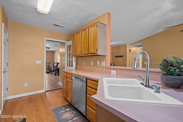 1005 Pleasant Dale Dr, Wilmington, NC 28412 - kitchen featuring dishwasher, light wood-type flooring, a textured ceiling, light countertops, and brown cabinetry