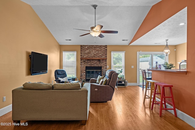 1005 Pleasant Dale Dr, Wilmington, NC 28412 - living room featuring a textured ceiling, a ceiling fan, lofted ceiling, wood finished floors, and a brick fireplace