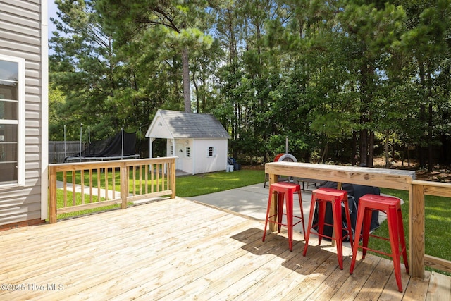 324 Foster Creek Rd, Swansboro, NC 28584 - wooden terrace featuring a trampoline, a lawn, a storage unit, and view of scattered trees