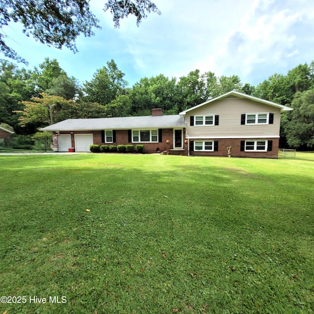 204 Tyree Rd, Kinston, NC 28504 - tri-level home featuring brick siding, a chimney, a front lawn, an attached garage, and view of scattered trees