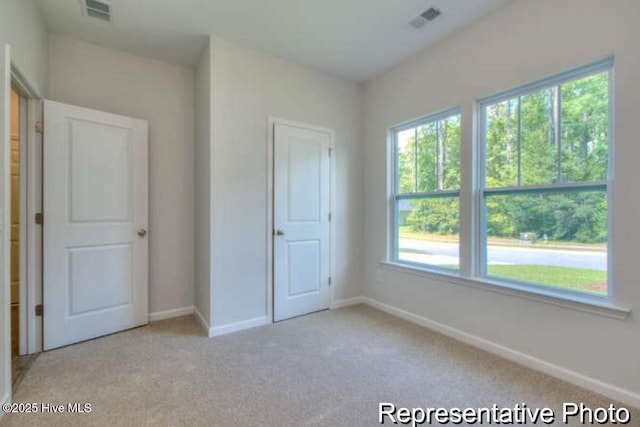 120 Forest Walk SW Unit 73, Sunset Beach, NC 28468 - unfurnished bedroom featuring light carpet and multiple windows