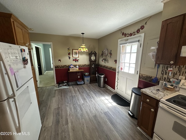 12760 S Pine Villa Dr, Laurinburg, NC 28352 - kitchen with white appliances, a textured ceiling, wood finished floors, pendant lighting, and light countertops