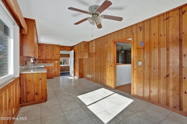 377 Louis Breeden Blvd, Hamlet, NC 28345 - kitchen with wooden walls, light countertops, a ceiling fan, brown cabinets, and light tile patterned floors