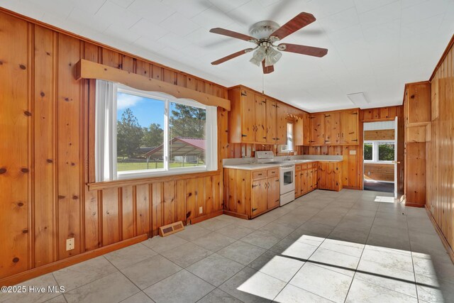 377 Louis Breeden Blvd, Hamlet, NC 28345 - kitchen featuring electric stove, wood walls, light countertops, a ceiling fan, and brown cabinetry