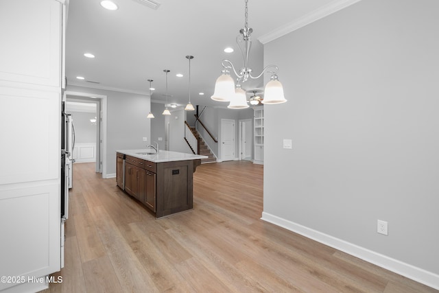 2955 Moorings Way SE, Southport, NC 28461 - kitchen featuring ornamental molding, recessed lighting, dark brown cabinets, a kitchen island with sink, and light wood-style flooring
