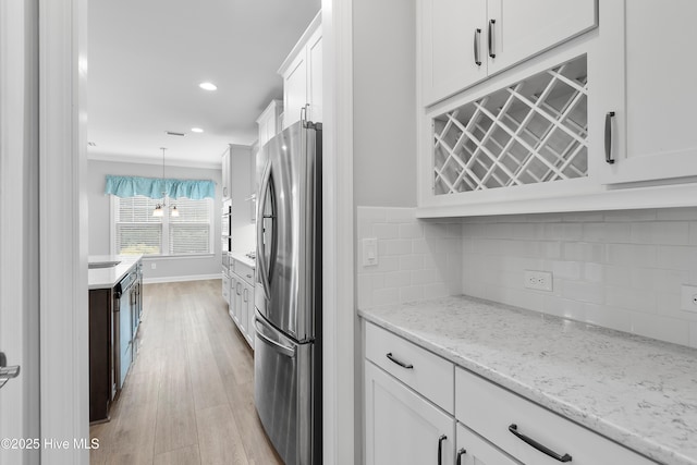2955 Moorings Way SE, Southport, NC 28461 - kitchen with freestanding refrigerator, white cabinetry, light wood-style flooring, backsplash, and light stone counters