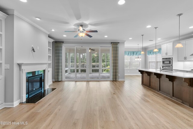 2955 Moorings Way SE, Southport, NC 28461 - unfurnished living room featuring ceiling fan, crown molding, recessed lighting, a premium fireplace, and light wood finished floors