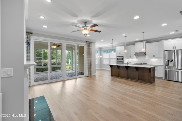 2955 Moorings Way SE, Southport, NC 28461 - kitchen featuring stainless steel appliances, a ceiling fan, a breakfast bar area, white cabinetry, and light countertops