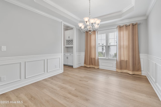 2955 Moorings Way SE, Southport, NC 28461 - empty room featuring a chandelier, light wood-type flooring, a decorative wall, crown molding, and wainscoting
