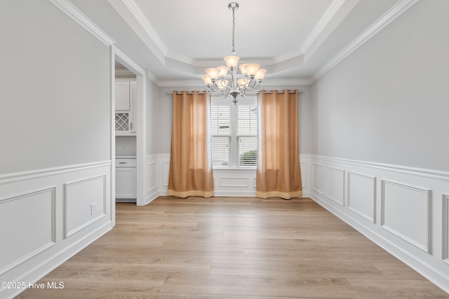 2955 Moorings Way SE, Southport, NC 28461 - unfurnished dining area with a chandelier, a decorative wall, a raised ceiling, light wood-style floors, and ornamental molding