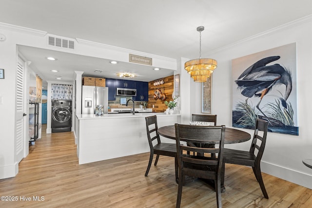 8801 Reed Dr Unit 303W, Emerald Isle, NC 28594 - dining space featuring washer / clothes dryer, crown molding, light wood-style flooring, a chandelier, and recessed lighting