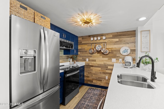 8801 Reed Dr Unit 303W, Emerald Isle, NC 28594 - kitchen with appliances with stainless steel finishes, blue cabinets, wooden walls, light countertops, and light wood-type flooring