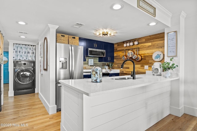 8801 Reed Dr Unit 303W, Emerald Isle, NC 28594 - kitchen with washer / dryer, stainless steel appliances, blue cabinetry, a peninsula, and crown molding