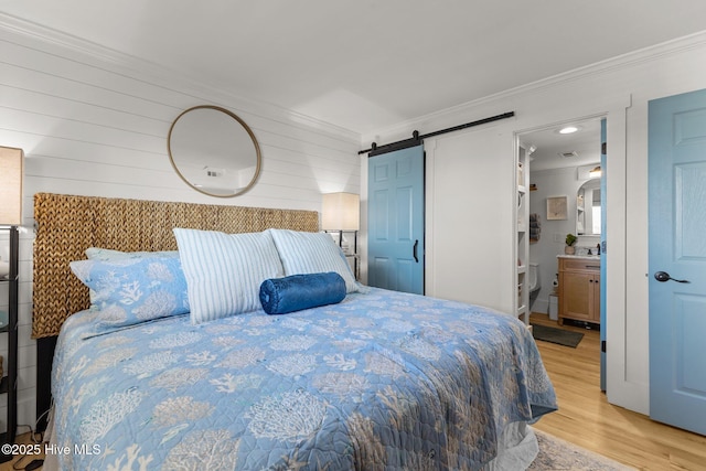 8801 Reed Dr Unit 303W, Emerald Isle, NC 28594 - bedroom with light wood-style floors, crown molding, a barn door, connected bathroom, and arched walkways