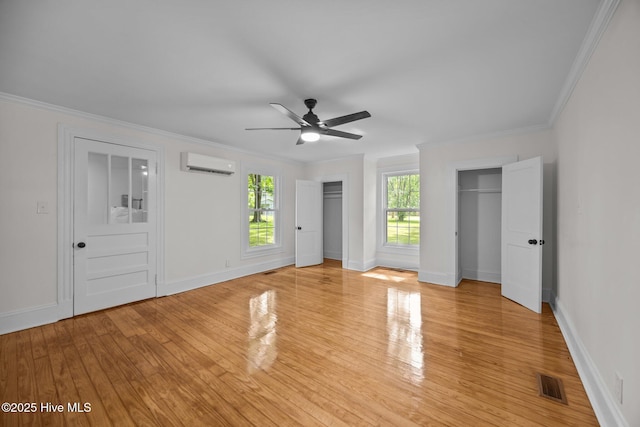 25967 US-264, Pantego, NC 27860 - unfurnished bedroom with an AC wall unit, two closets, crown molding, light wood-type flooring, and a ceiling fan