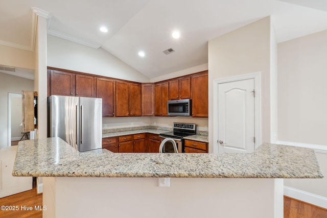 3716 Pond Pine Ct, Southport, NC 28461 - kitchen featuring appliances with stainless steel finishes, a kitchen breakfast bar, light wood finished floors, light stone counters, and vaulted ceiling