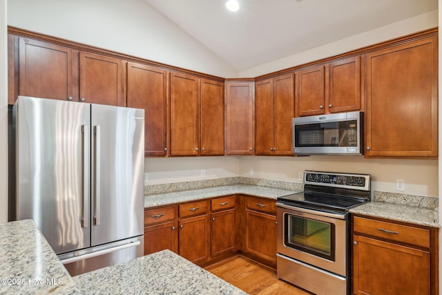 3716 Pond Pine Ct, Southport, NC 28461 - kitchen featuring stainless steel appliances, lofted ceiling, light wood finished floors, and brown cabinets