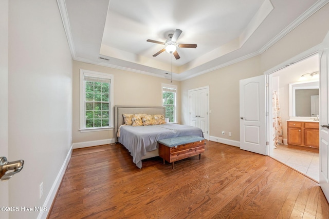 3716 Pond Pine Ct, Southport, NC 28461 - bedroom with a tray ceiling, light wood-type flooring, crown molding, ensuite bath, and a ceiling fan