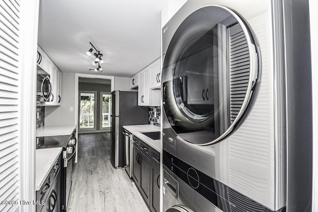 130 Salter Path Rd Unit 74, Pine Knoll Shores, NC 28512 - washroom with light wood-type flooring, estacked washer and dryer, and rail lighting