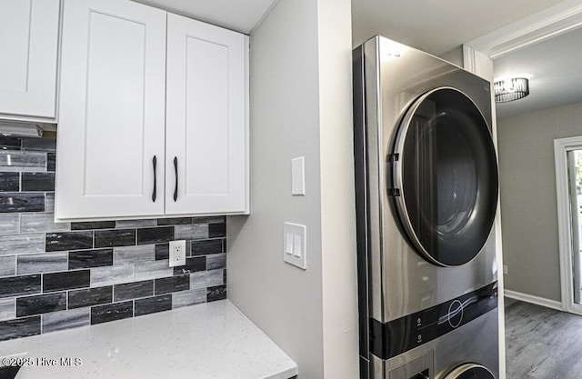 130 Salter Path Rd Unit 74, Pine Knoll Shores, NC 28512 - laundry room featuring stacked washer and clothes dryer, wood finished floors, and cabinet space