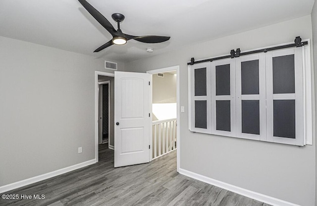 130 Salter Path Rd Unit 74, Pine Knoll Shores, NC 28512 - unfurnished bedroom with a barn door, wood finished floors, and a ceiling fan