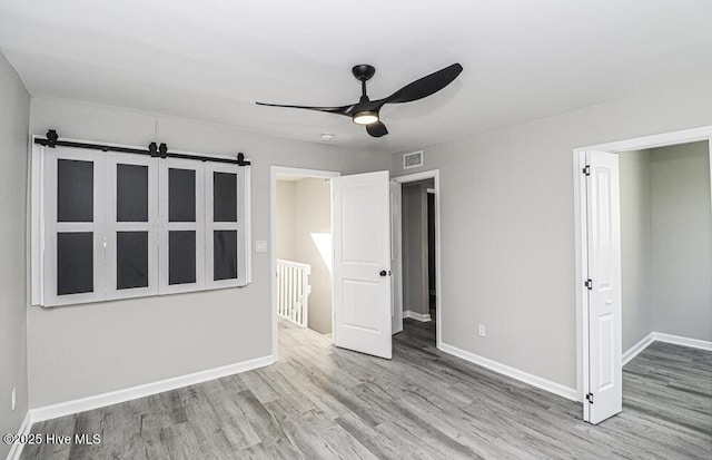 130 Salter Path Rd Unit 74, Pine Knoll Shores, NC 28512 - unfurnished bedroom with wood finished floors, a barn door, and a ceiling fan