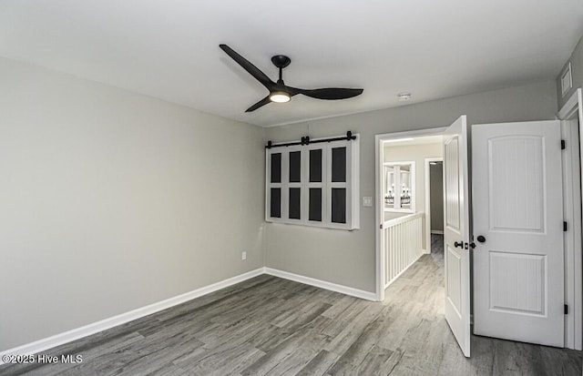 130 Salter Path Rd Unit 74, Pine Knoll Shores, NC 28512 - spare room with wood finished floors, a ceiling fan, a barn door, and a smoke detector