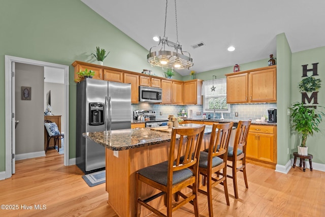 133 Graystone Rd, Wilmington, NC 28411 - kitchen with appliances with stainless steel finishes, tasteful backsplash, light wood-type flooring, a center island, and a breakfast bar