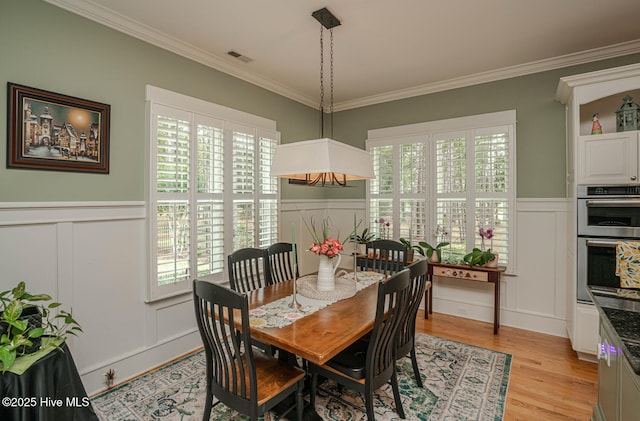 595 Wicklow Sq SW, Ocean Isle Beach, NC 28469 - dining area with a decorative wall, wainscoting, crown molding, healthy amount of natural light, and light wood finished floors