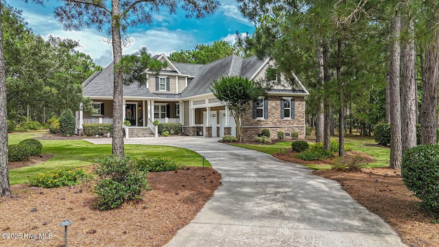 595 Wicklow Sq SW, Ocean Isle Beach, NC 28469 - view of front facade featuring a porch, stone siding, concrete driveway, a standing seam roof, and a front yard