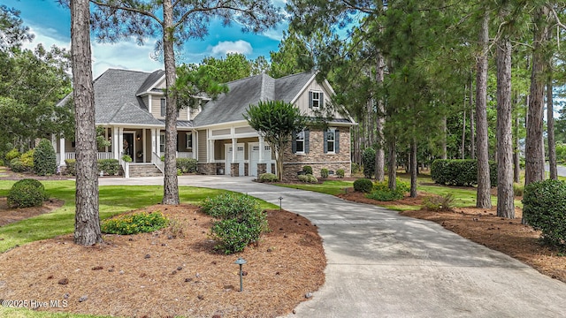 595 Wicklow Sq SW, Ocean Isle Beach, NC 28469 - view of front of home with curved driveway, stone siding, a porch, a garage, and a front yard