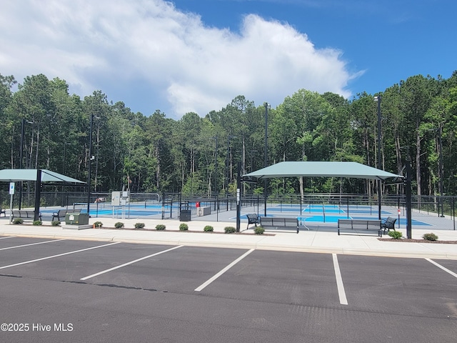 595 Wicklow Sq SW, Ocean Isle Beach, NC 28469 - uncovered parking lot with a tennis court and a view of trees