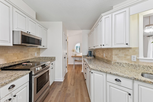 103 Coppers Trl, Wilmington, NC 28411 - kitchen featuring appliances with stainless steel finishes, white cabinets, light wood finished floors, light stone counters, and decorative backsplash