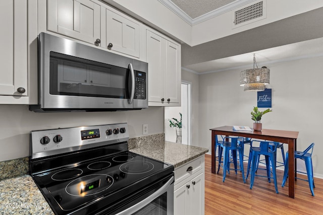 1004 Carolina Beach Ave S Unit B6, Carolina Beach, NC 28428 - kitchen featuring appliances with stainless steel finishes, ornamental molding, light wood-type flooring, a chandelier, and white cabinets