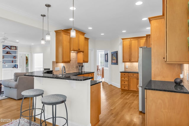1514 Grandiflora Dr, Leland, NC 28451 - kitchen featuring a peninsula, a kitchen bar, ornamental molding, light wood-type flooring, and freestanding refrigerator