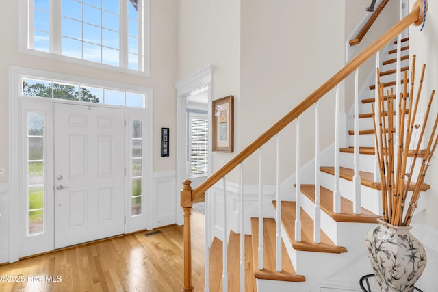 1514 Grandiflora Dr, Leland, NC 28451 - foyer entrance with wood finished floors, a towering ceiling, stairway, wainscoting, and a decorative wall