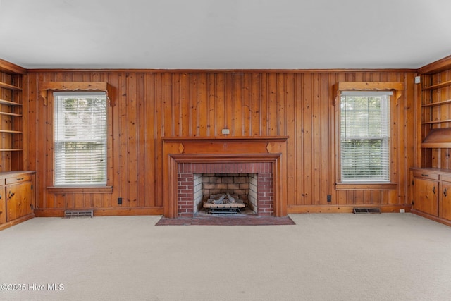 6074 NC-42 Hwy W, Macclesfield, NC 27852 - unfurnished living room with wood walls, carpet flooring, a fireplace, and built in shelves