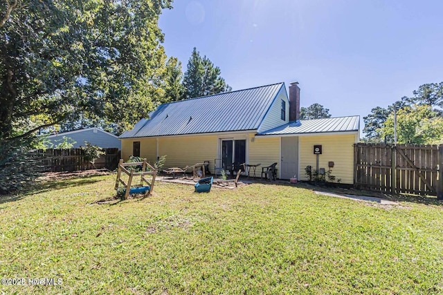 105 Woodside Ct, Jacksonville, NC 28546 - rear view of house with a chimney, a fenced backyard, a metal roof, and a patio area