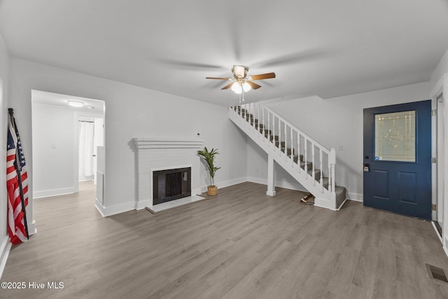 350 Hubert Blvd, Hubert, NC 28539 - unfurnished living room featuring stairs, ceiling fan, wood finished floors, and a brick fireplace