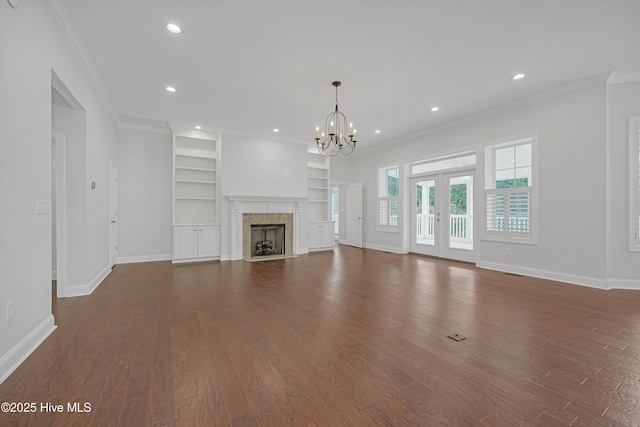 311 S Kingfisher Ln, Hampstead, NC 28443 - unfurnished living room featuring dark wood-style floors, a chandelier, crown molding, built in features, and recessed lighting