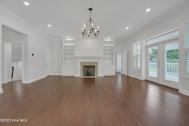 311 S Kingfisher Ln, Hampstead, NC 28443 - unfurnished living room with a chandelier, dark wood finished floors, built in features, a premium fireplace, and crown molding