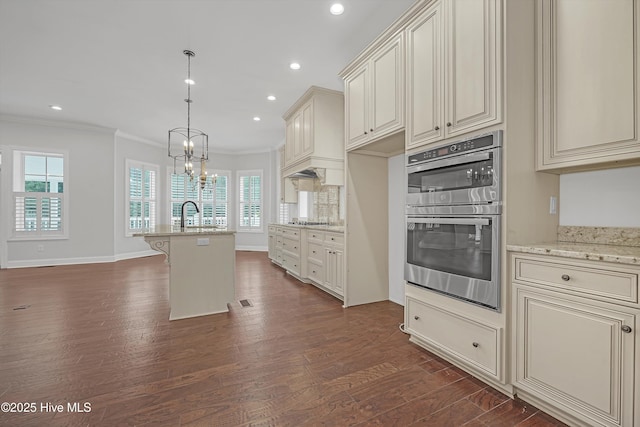 311 S Kingfisher Ln, Hampstead, NC 28443 - kitchen featuring double oven, cream cabinets, crown molding, a chandelier, and stovetop