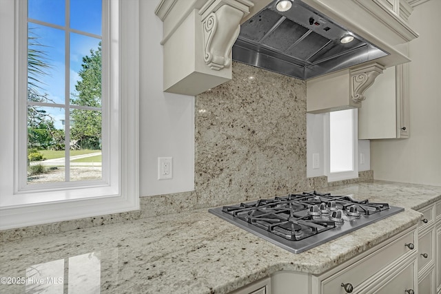 311 S Kingfisher Ln, Hampstead, NC 28443 - kitchen with stainless steel gas stovetop, wall chimney exhaust hood, white cabinets, and light stone countertops