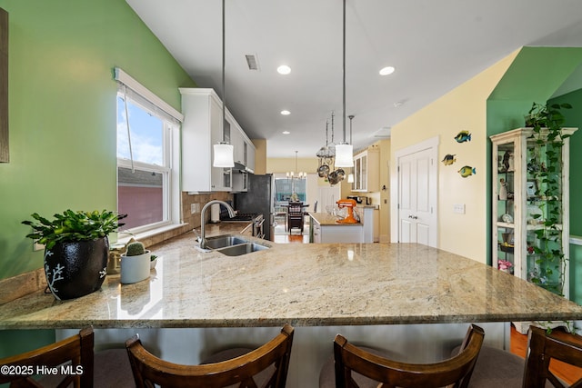 1602 Carolina Beach Ave N Unit 2, Carolina Beach, NC 28428 - kitchen featuring white cabinets, hanging light fixtures, a breakfast bar, light stone counters, and recessed lighting