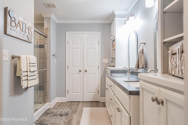 409 S Grace Chapel Church Rd, Hamlet, NC 28345 - bathroom featuring a stall shower, wood finished floors, double vanity, and ornamental molding