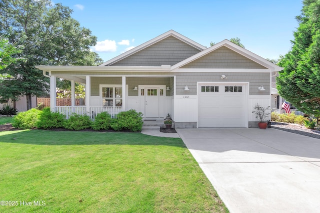 102 SW 4th St, Oak Island, NC 28465 - view of front of property featuring an attached garage, driveway, a front lawn, and a porch