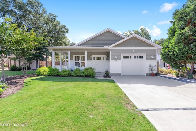 102 SW 4th St, Oak Island, NC 28465 - view of front of house with an attached garage, a porch, concrete driveway, and a front yard