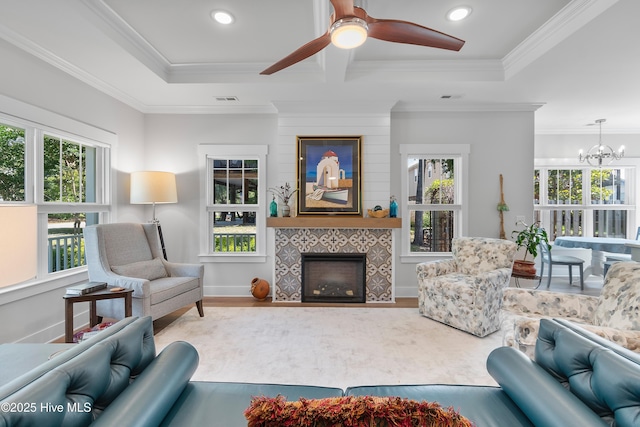 102 SW 4th St, Oak Island, NC 28465 - living area with a tiled fireplace, ceiling fan, wood finished floors, ornamental molding, and a chandelier